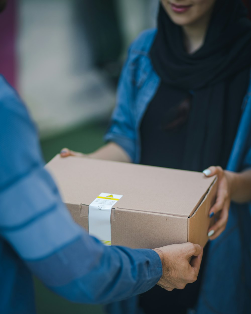 Two people passing a taped shipping box across a counter